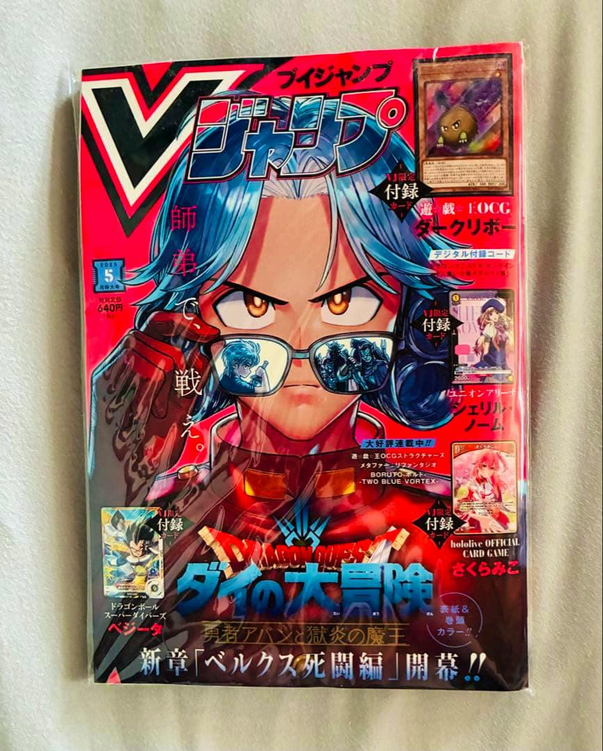Shrink-wrapped Vジャンプ magazine (May 2025 issue) showing an illustrated blue-haired character wearing glasses with reflections and several small promotional card images on the cover.