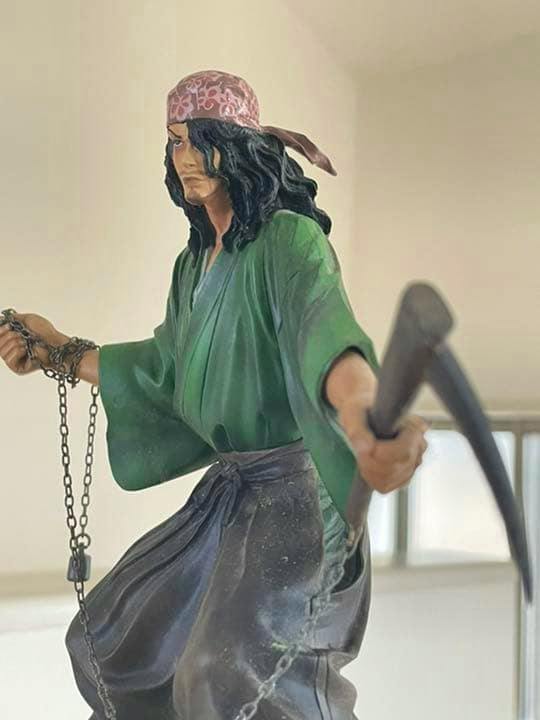 Front three-quarter view of the バガボンド 宍戸梅軒 plastic figure wearing a green robe and holding a chained scythe.