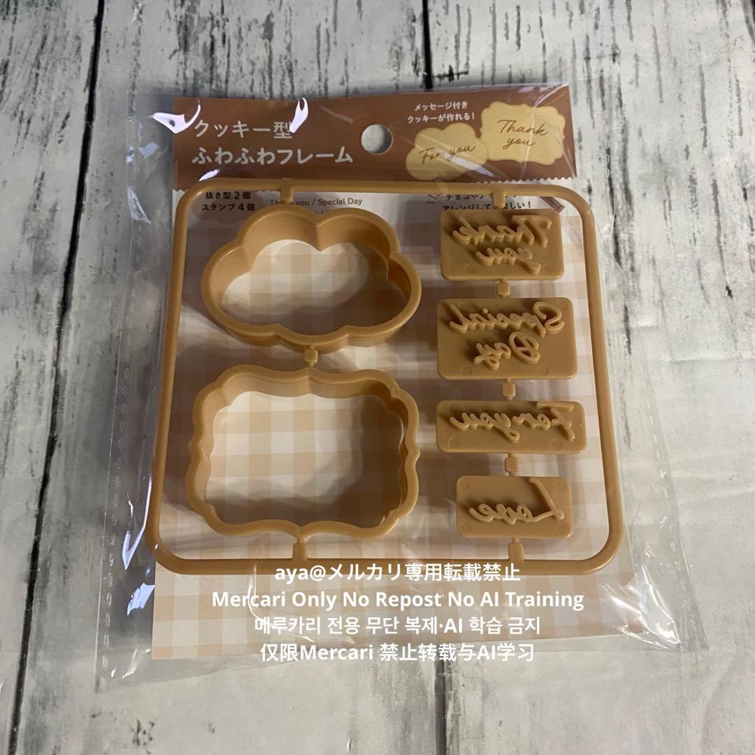 Packaged cookie cutter set showing two frame-shaped cutters and four small message stamp cutters in clear plastic packaging on a wooden surface.