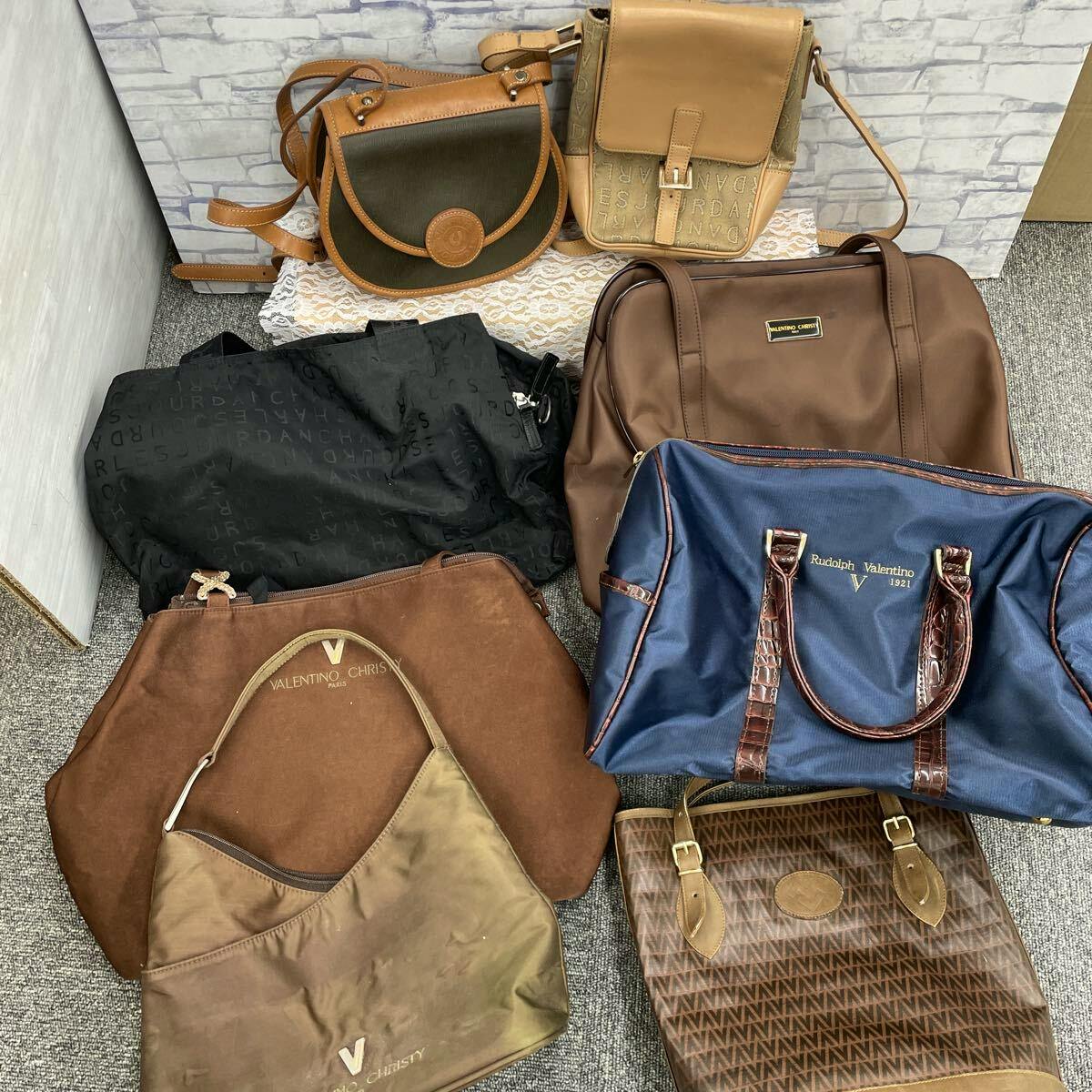 Bulk set of assorted handbags and canvas bags arranged together on the floor, showing various brown, navy, and tan colors.