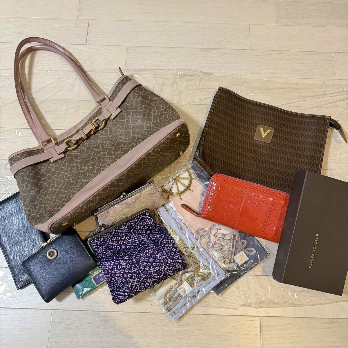 Several handbags, wallets, and small accessories arranged on a light wood floor, shown as a grouped lot.