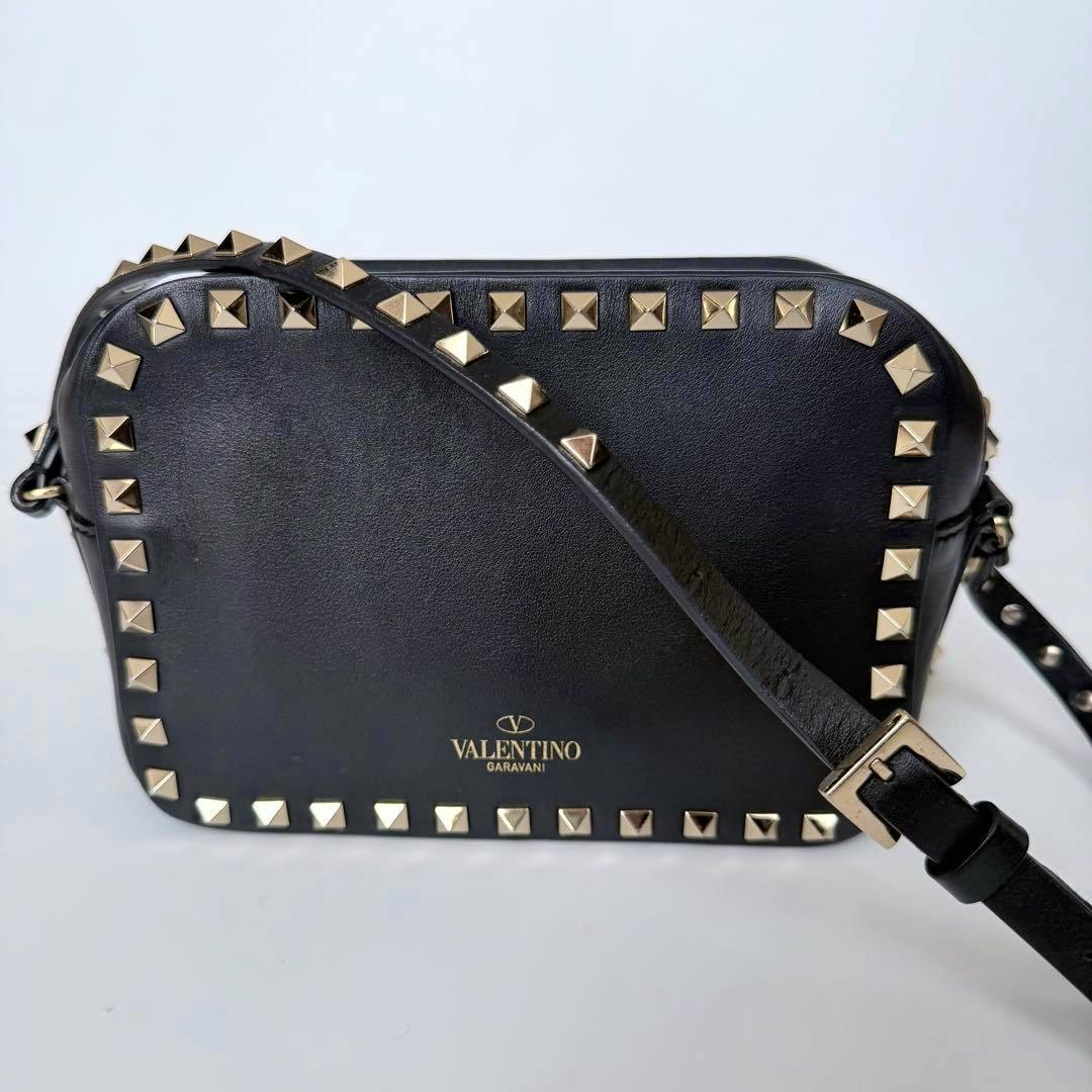 Front view of a black VALENTINO Rockstud shoulder bag with gold pyramid studs and an adjustable shoulder strap.