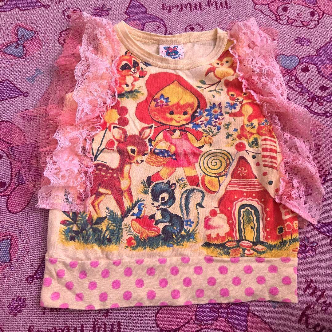 Children's cotton shirt with pink lace sleeves, a colorful illustration of a girl and forest animals, and a pink polka-dot hem.