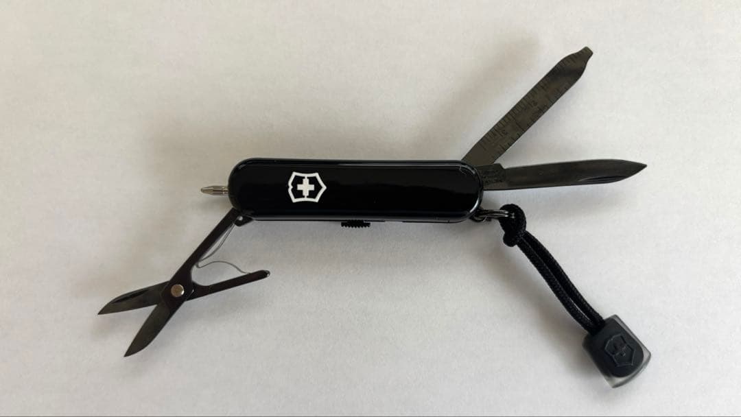 Black Victorinox Signature Lite Onyx Black pocket knife shown open on a white background with scissors, a blade, and a file (and a lanyard) visible.