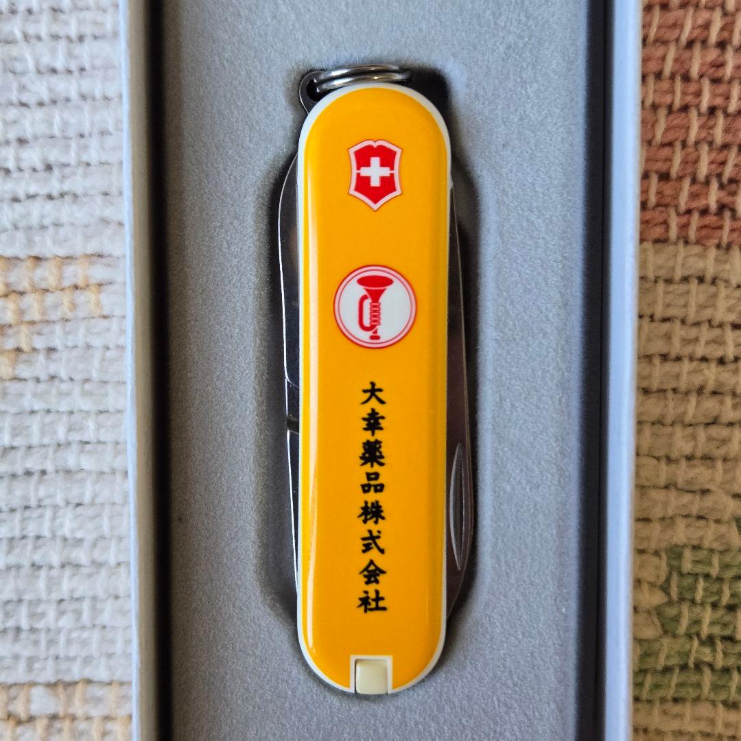 Yellow Victorinox pocket knife showing the Swiss shield and vertical Japanese text on one side, displayed in a foam tray.