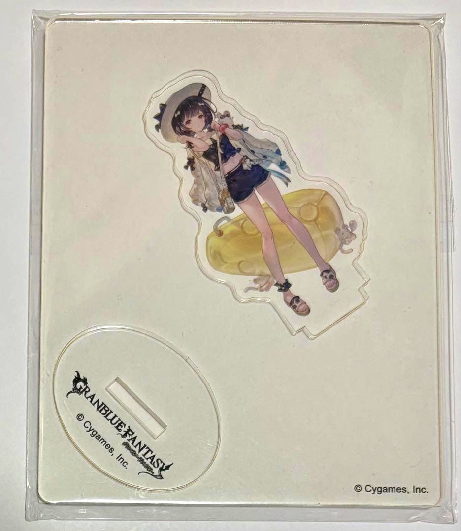 A packaged acrylic decorative stand showing a swimsuit-illustrated character and its oval "Granblue Fantasy" display base on white backing.