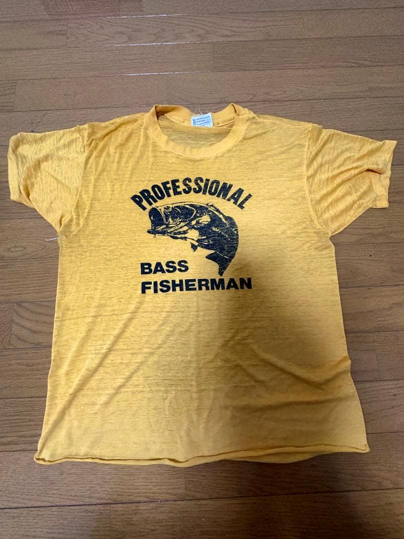 Yellow men's cotton T-shirt laid flat showing an arched "PROFESSIONAL" print, a bass fish graphic, and "BASS FISHERMAN" text on the front.