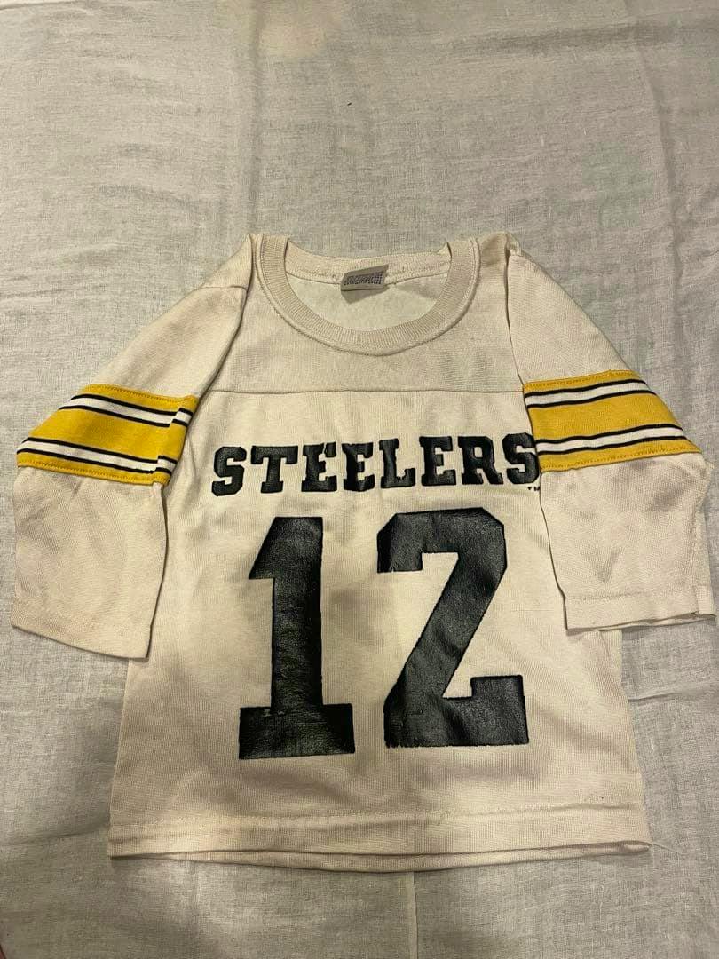 Laid-flat vintage children's white long-sleeve cotton T-shirt with "STEELERS" across the chest, a large black printed number below, and yellow-striped sleeves.