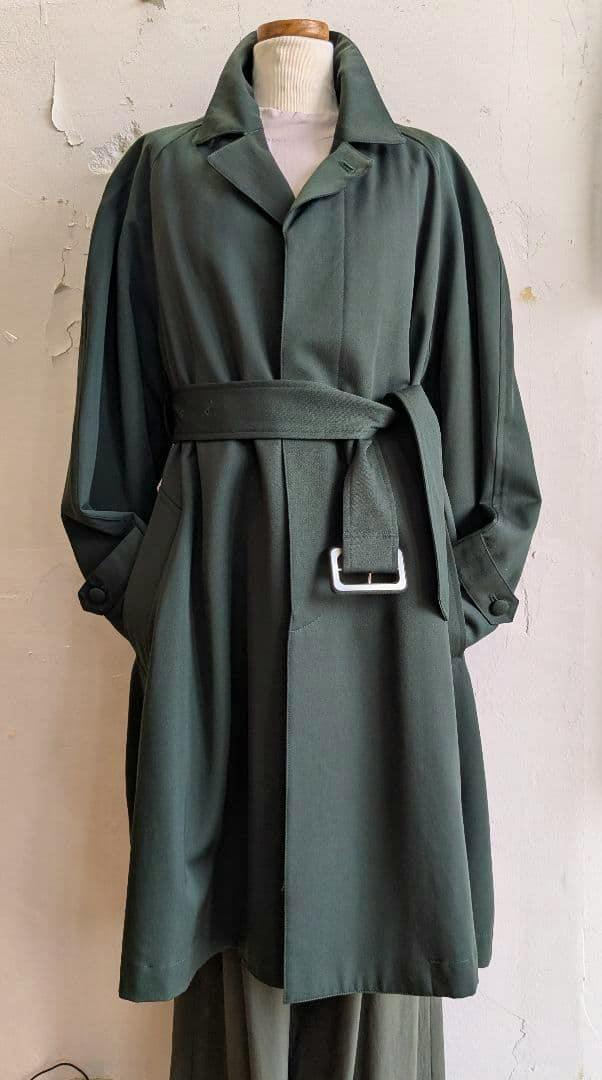 Front view of a dark green wool women's coat belted on a mannequin.