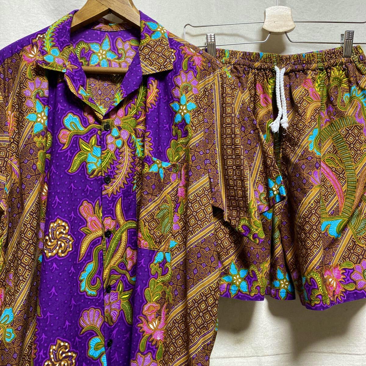 Purple and brown vintage batik short-sleeve open-collar men's shirt with matching shorts hanging side by side.