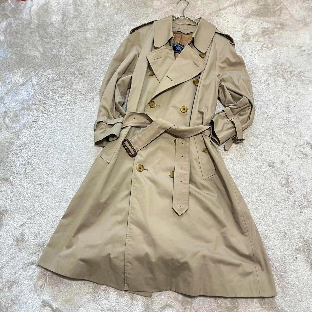Beige Burberry trench coat laid flat showing double-breasted front, belt, and epaulettes.