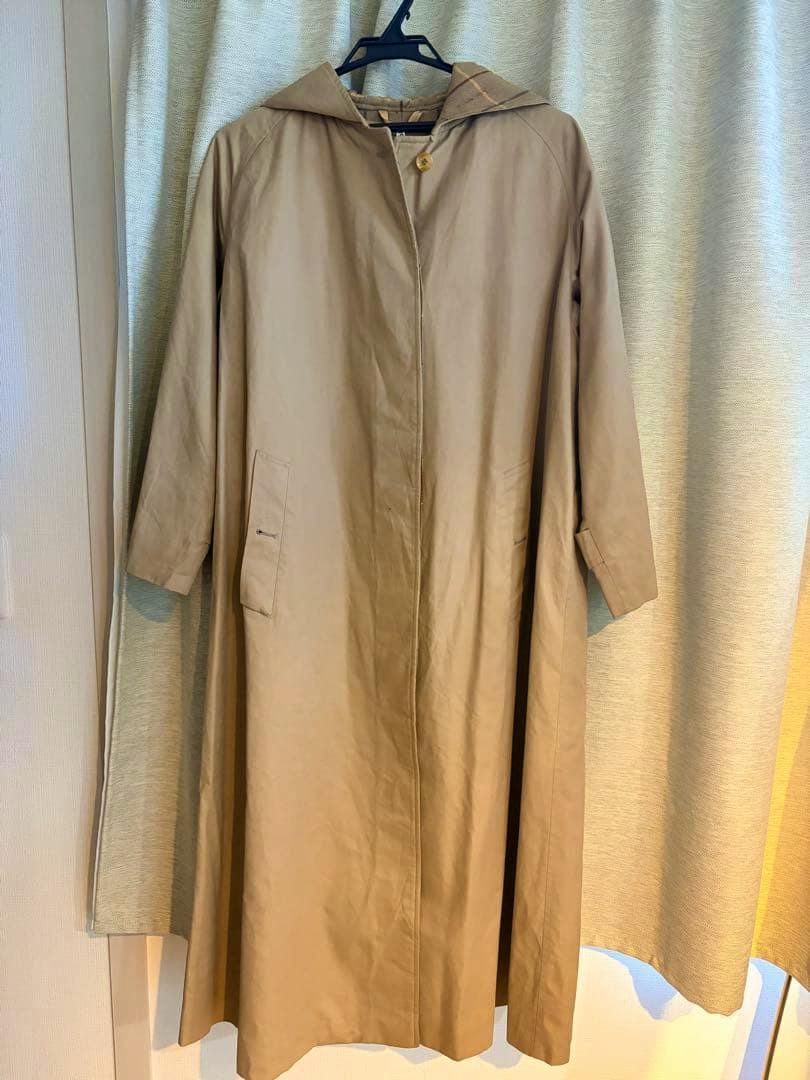 Front view of a vintage beige hooded long women's coat hanging on a hanger.