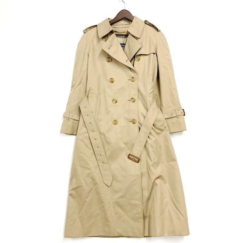 Beige women's trench coat with double-breasted buttons and a belt displayed on a hanger against a white background.
