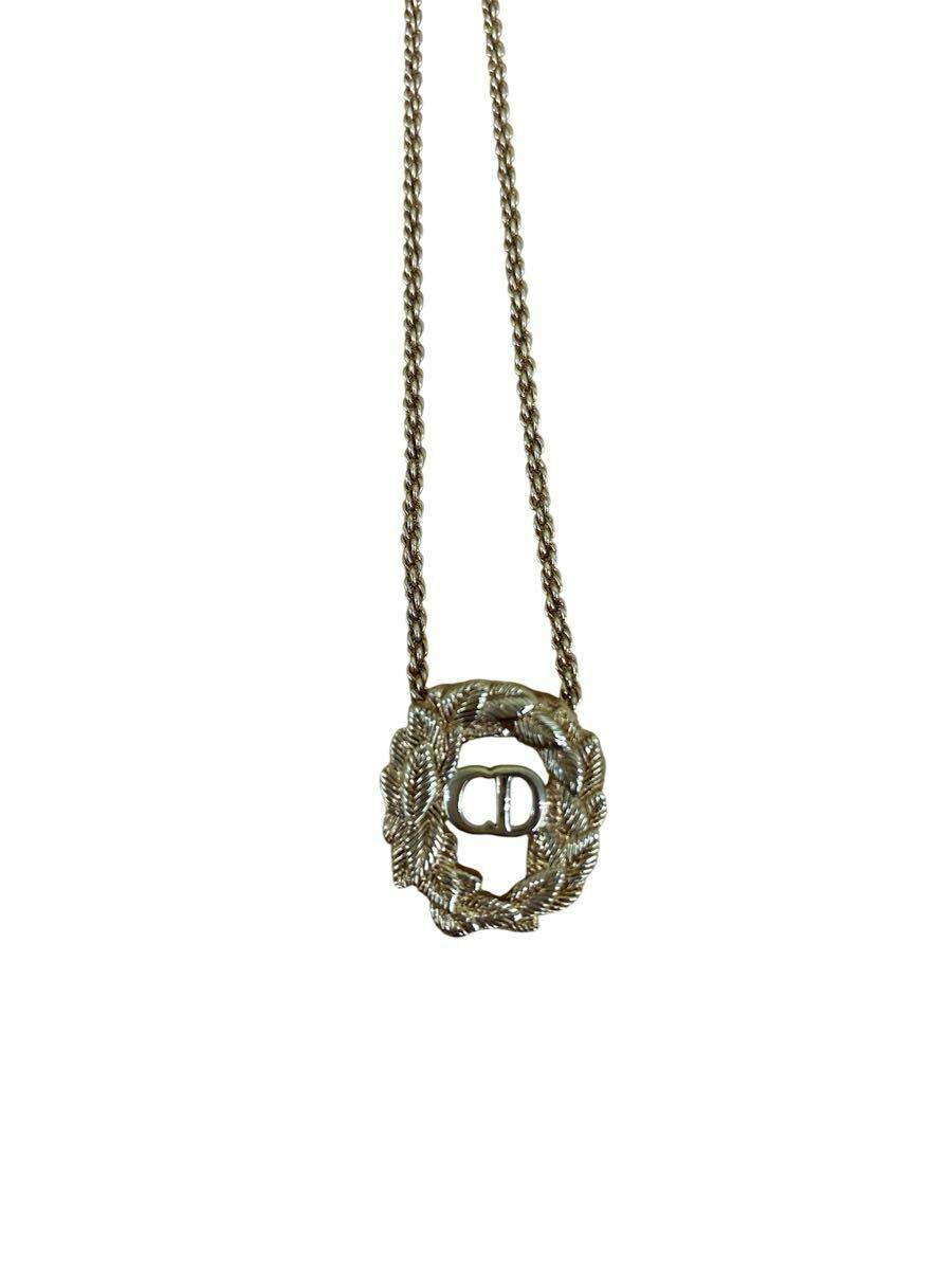 Gold-colored vintage Christian Dior CD logo leaf pendant necklace on a white background.