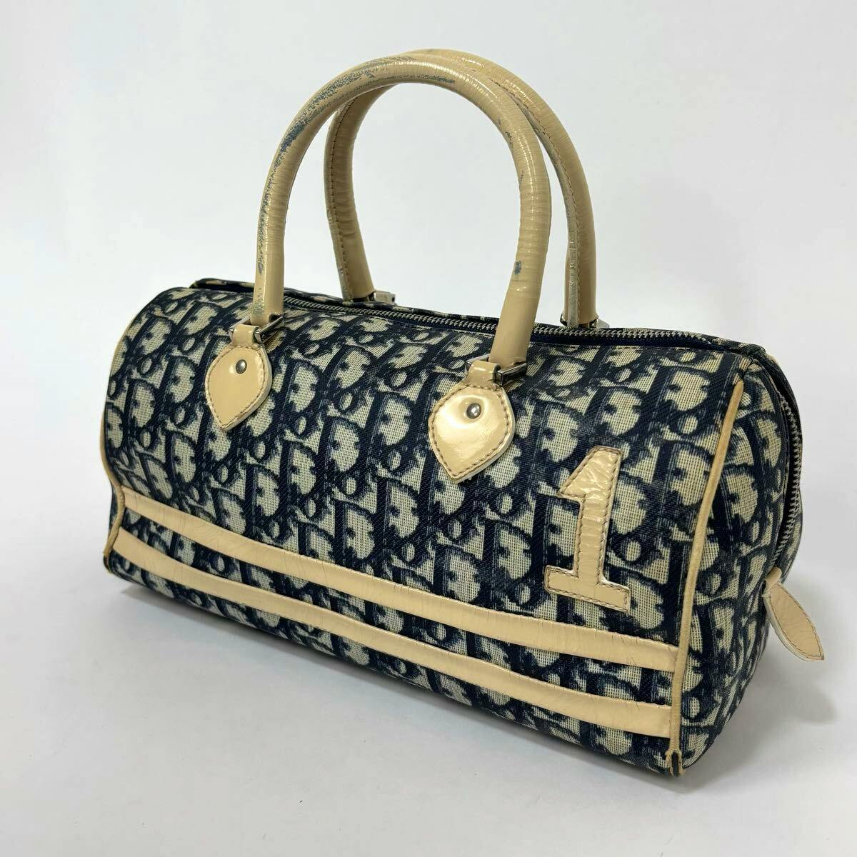 Christian Dior canvas mini boston handbag in navy trotter pattern with beige leather trim and handles shown at an angle.