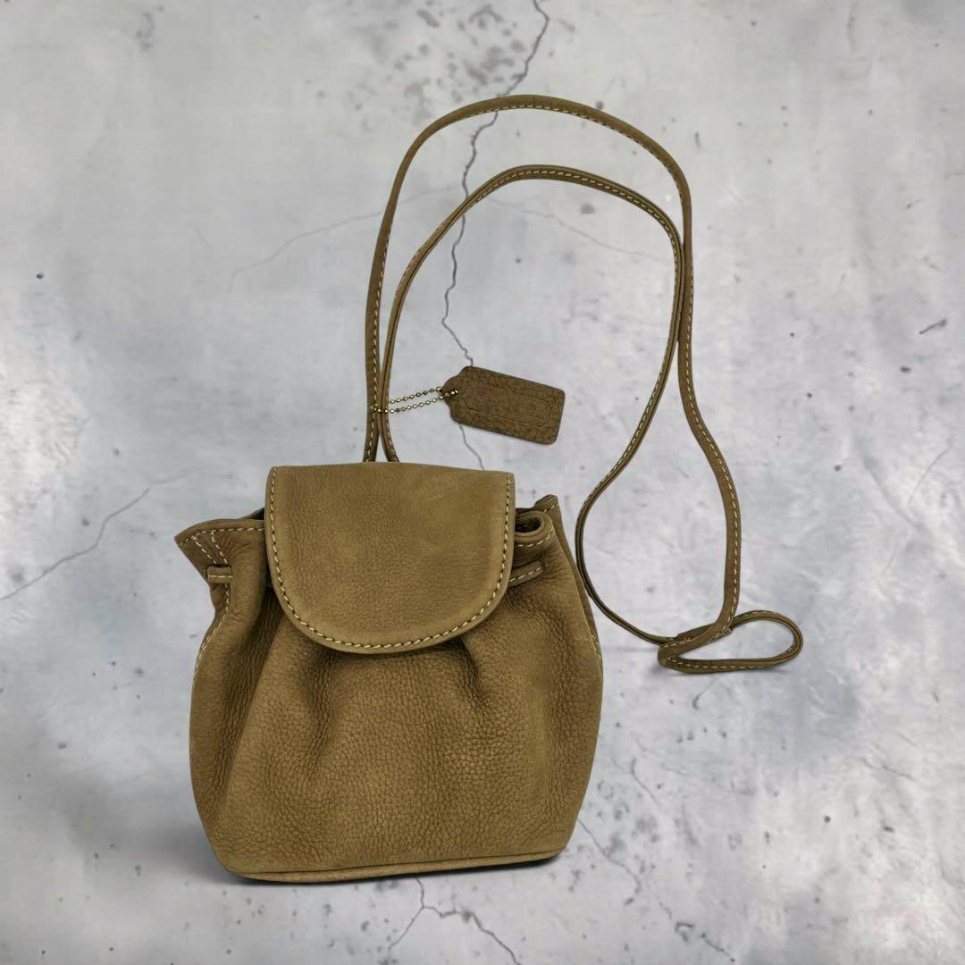 Vintage Coach 4940 nubuck mini shoulder bag with flap closure, long strap, and hang tag on a light marbled background.