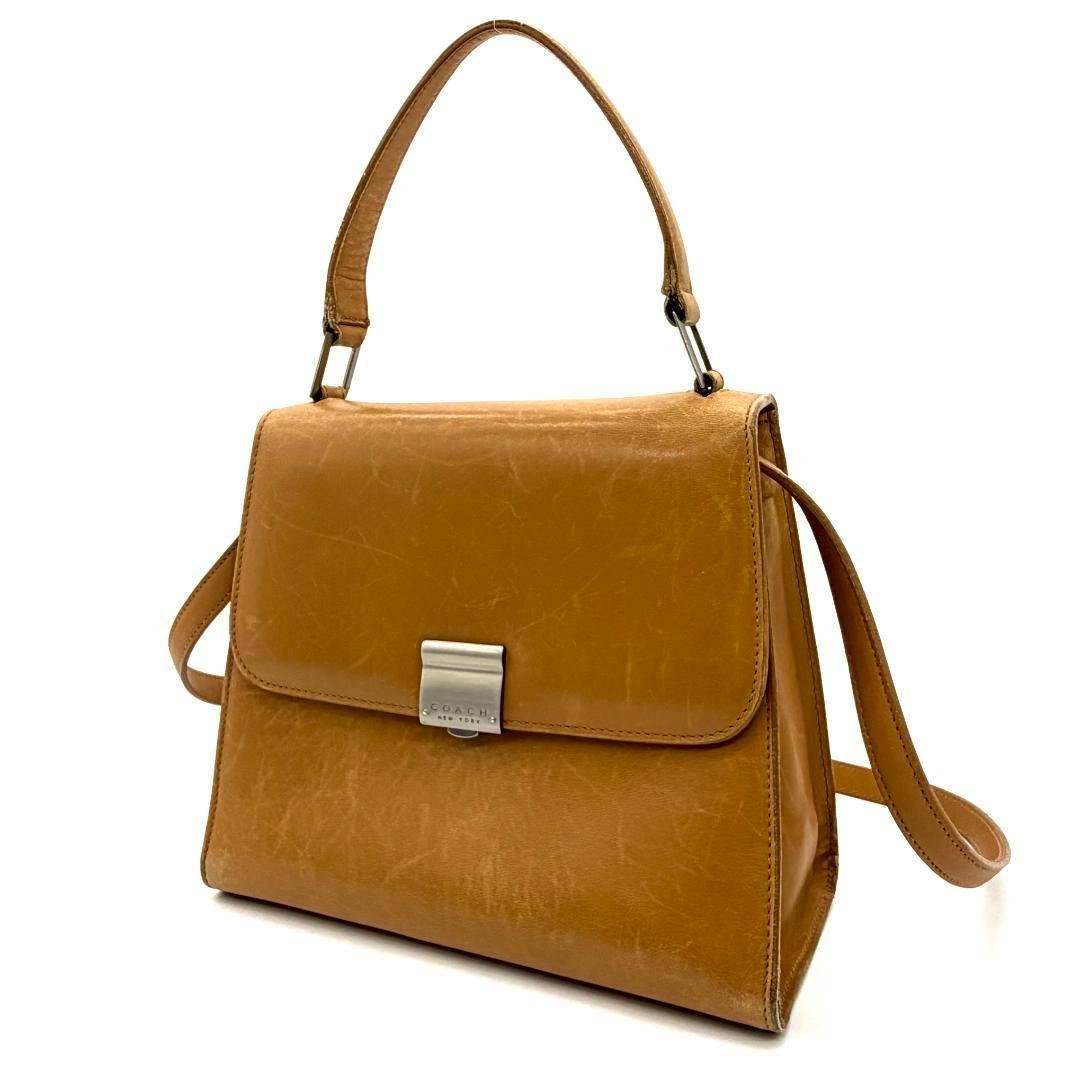 Tan leather Coach hand bag shoulder bag shown at a three-quarter angle with top handle and long shoulder strap visible on a white background.
