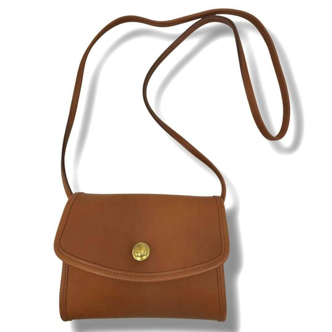 Brown leather Coach shoulder handbag with long strap and a rounded flap secured by a gold snap, shown on a white background.