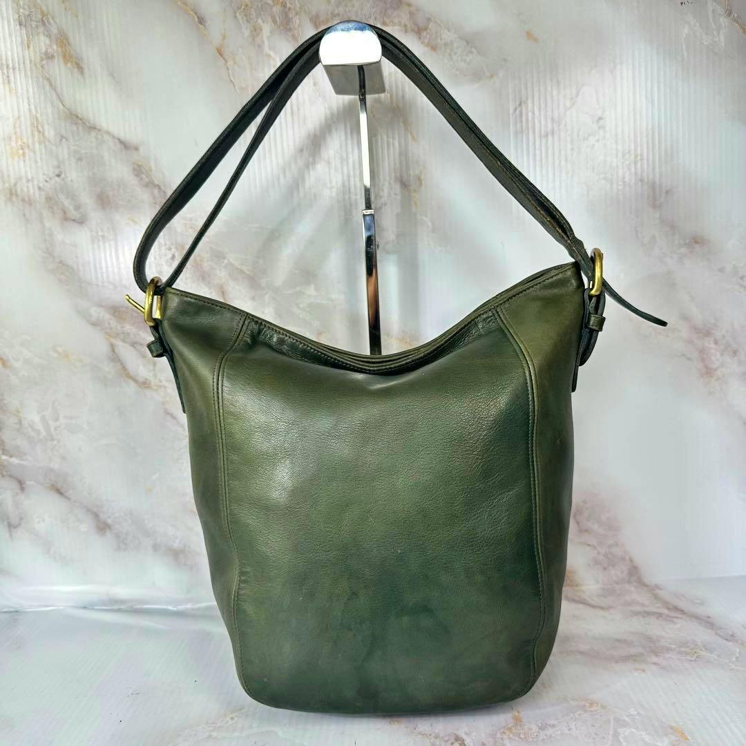 OLD COACH green cow leather shoulder duffle bag shown front-facing on a metal display stand.