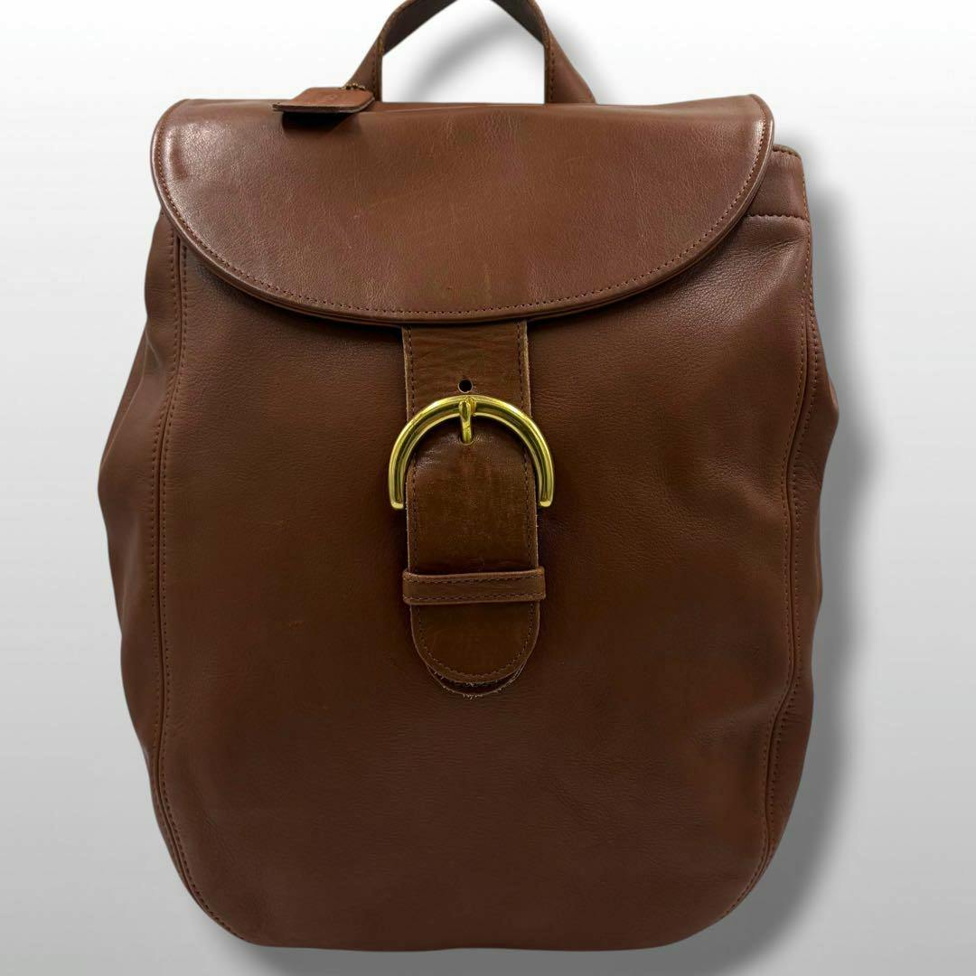 Front view of the OLD COACH brown leather backpack showing the flap closure and gold-tone buckle.