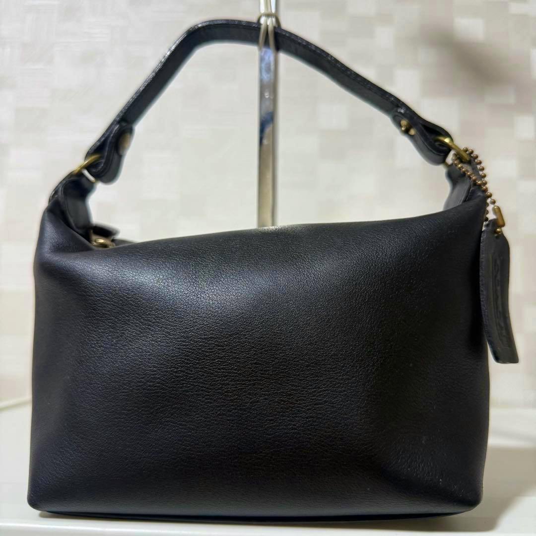 Front view of the black leather vintage Old Coach accessory pouch handbag with a short handle and a leather tag.