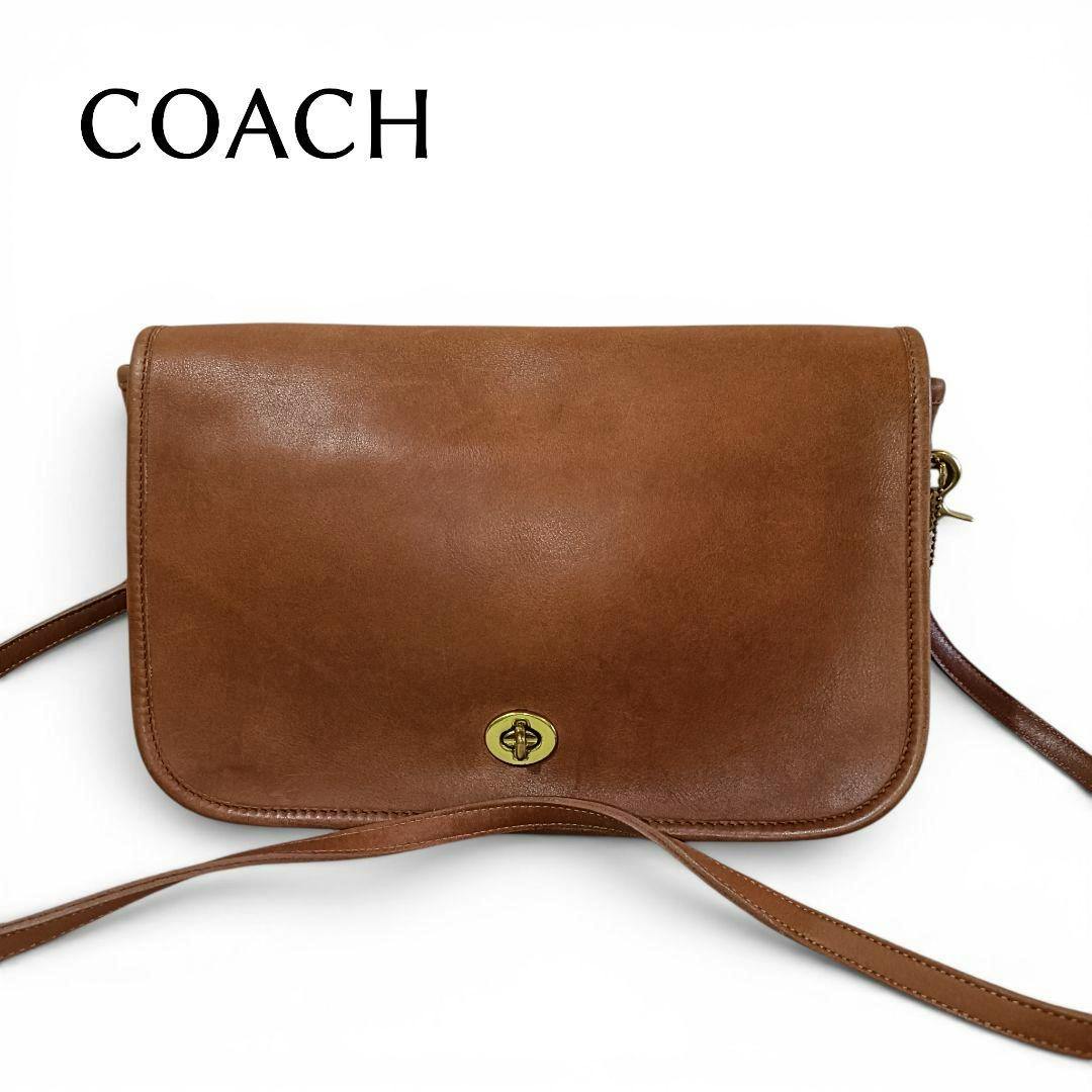 Front view of a brown leather COACH shoulder bag with a turn-lock closure and long strap.