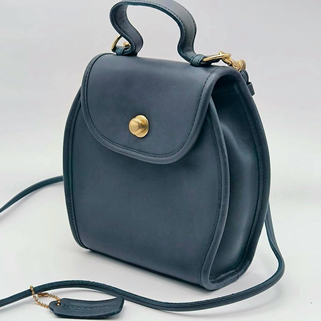 Mini Coach cow leather shoulder bag with top handle and a gold German snap closure shown on a white background.