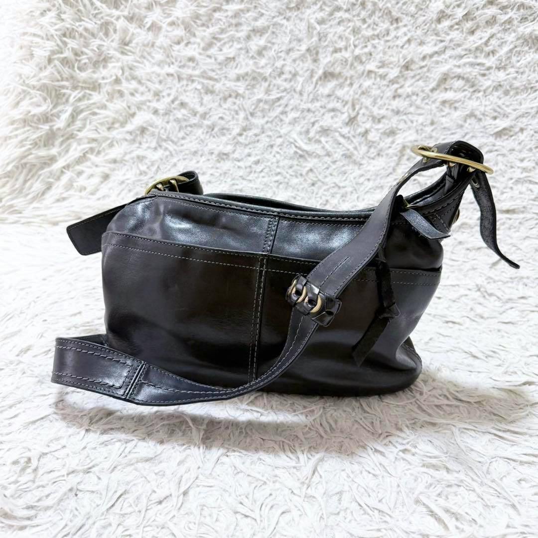 Black Coach cow-leather one-shoulder bag shown from the side on a white shag background.