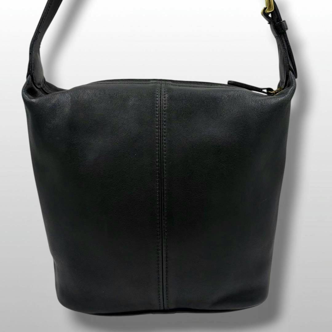 Front view of a black Coach shoulder bag showing the leather body, center seam, and shoulder strap.