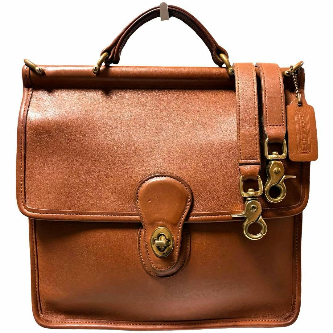 Front view of a vintage Coach Willis brown cow leather 2-way bag with top handle, flap with turn-lock, and detachable strap with brass hardware.