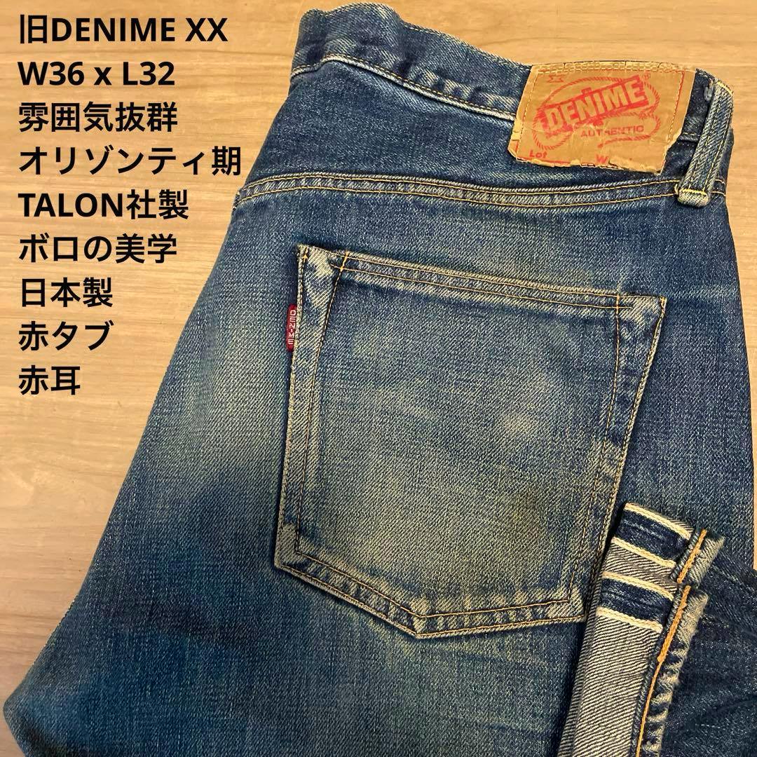 Folded men's denim jeans showing the back pocket, red tab, selvedge cuff, and leather brand patch.