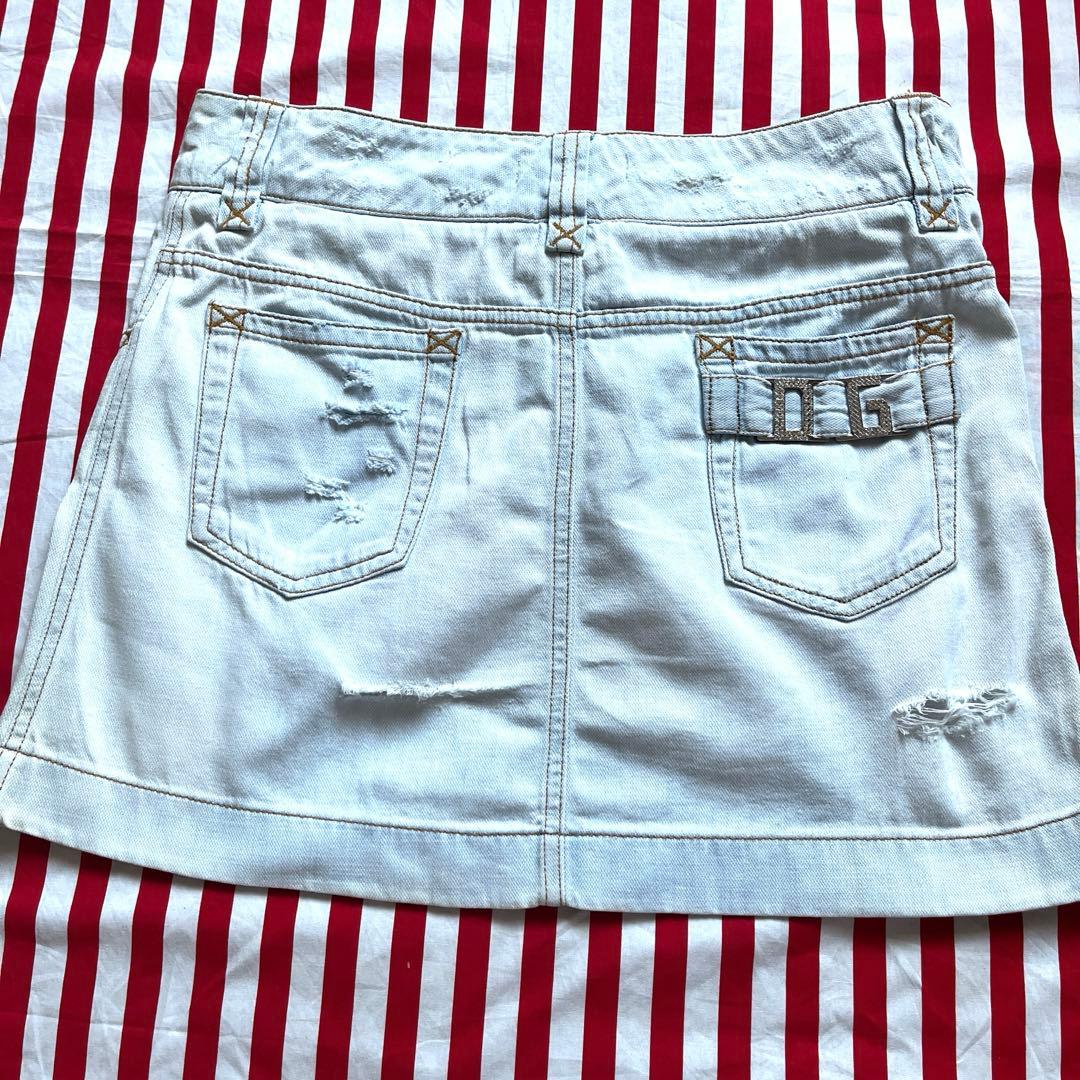 Back view of a bleached light denim women's mini skirt laid flat, showing two back pockets and distressed details.