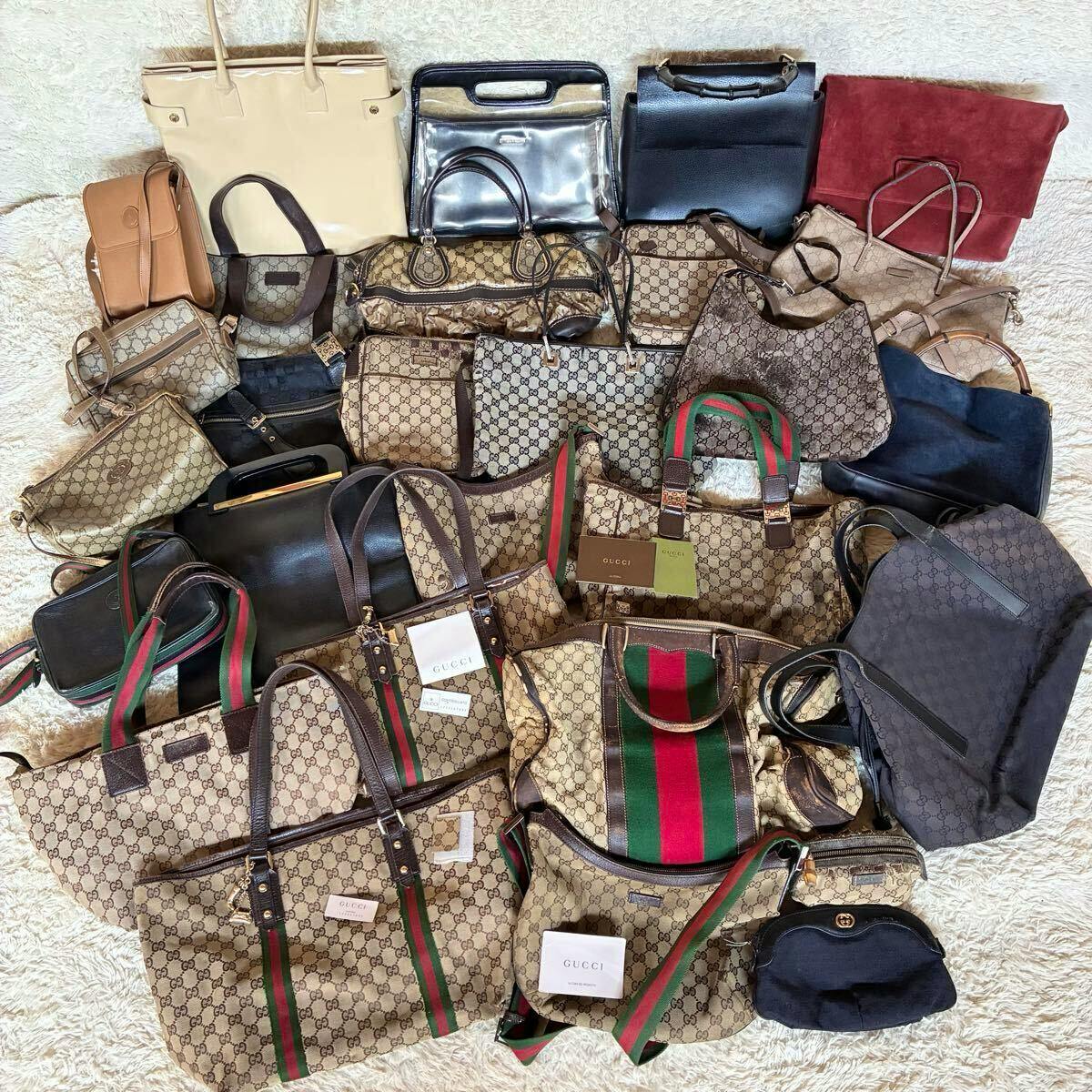 Overview of a large lot of Gucci bags and purses with GG monogram and red-green webbing, arranged on a light rug.