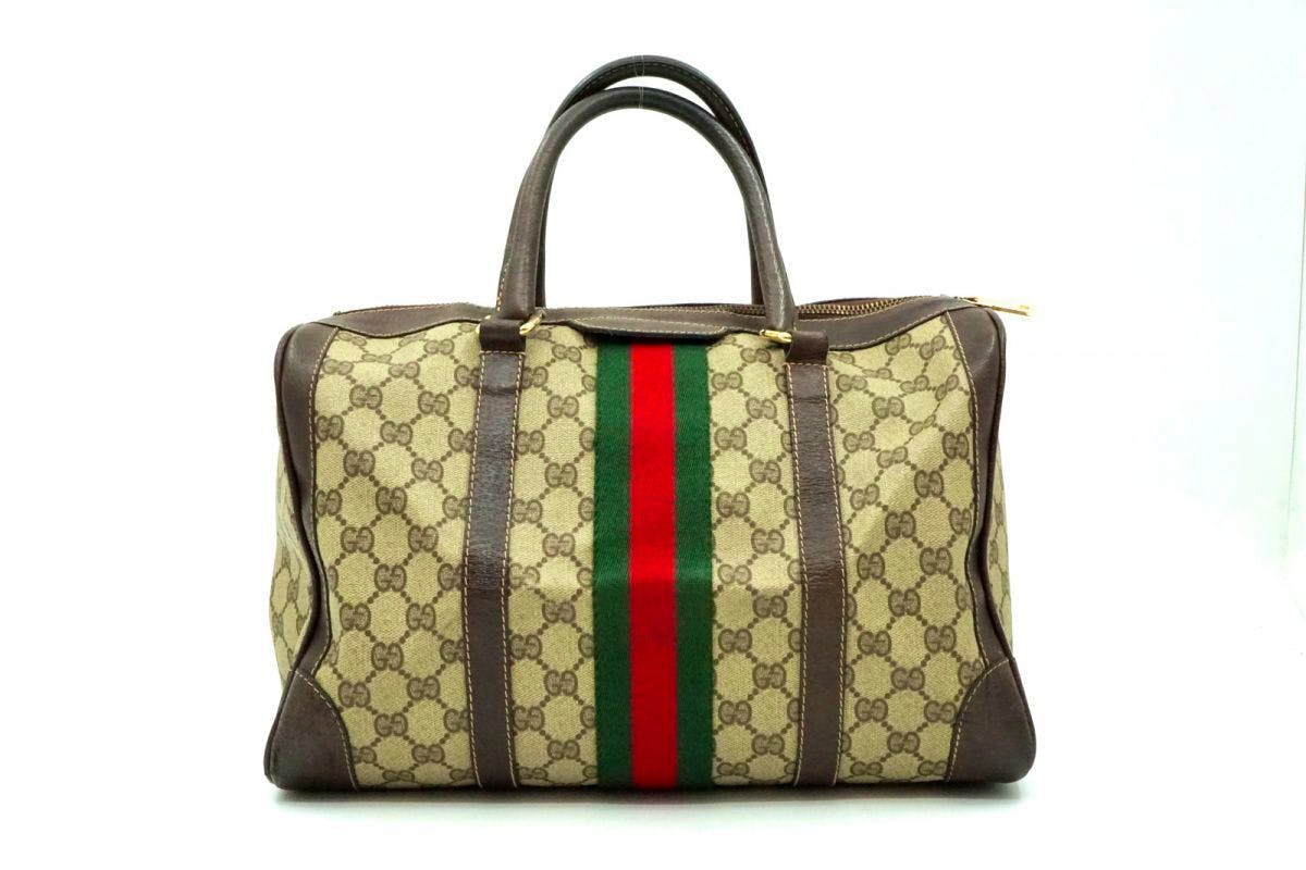 Front view of a vintage Gucci GG monogram canvas handbag with brown leather trim, twin handles, and a central green-red-green Web stripe.