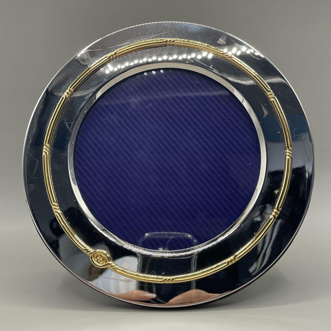 Front view of a round silver Deadstock Old Gucci photo frame with a gold decorative inner ring and a blue circular insert.