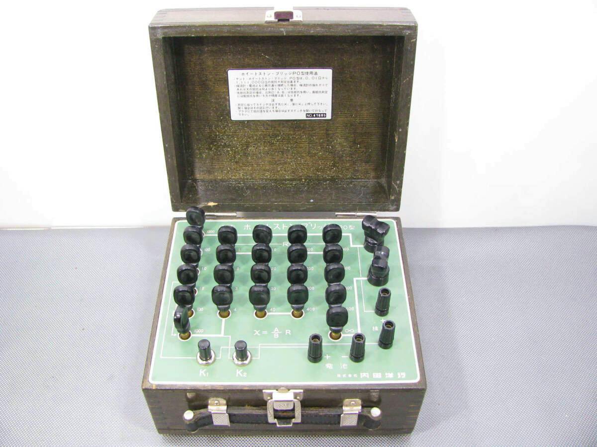 Open wooden case showing the vintage Wheatstone-bridge PO-type panel with multiple black binding posts and a label inside the lid.