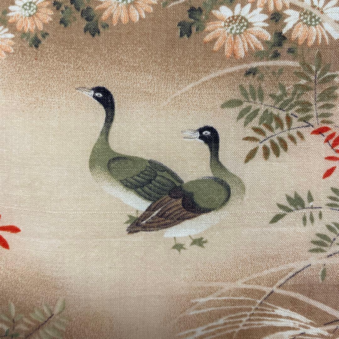 Close-up of a silk kimono fabric scrap showing two green birds with black heads and surrounding floral motifs on a beige background.