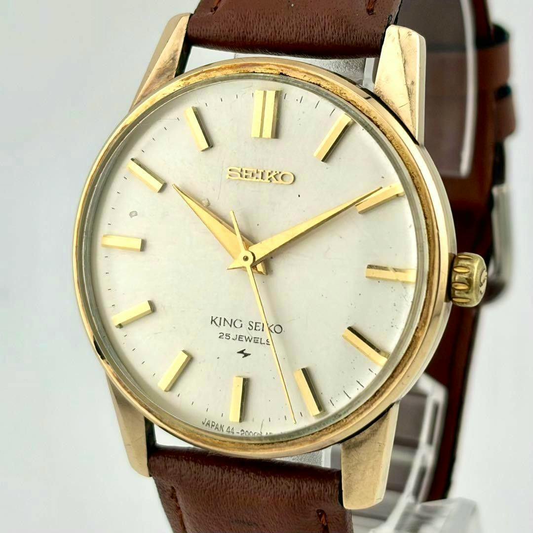 Close-up of a King Seiko 44-2000 vintage hand-wind wristwatch with a white dial, gold-tone markers and a brown leather strap.