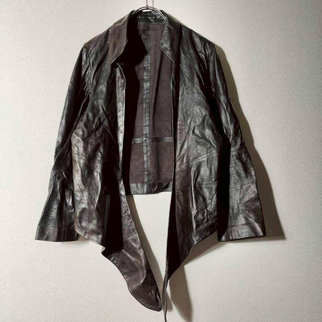 A cropped, thin vintage lamb leather jacket hanging on a hanger against a plain wall.