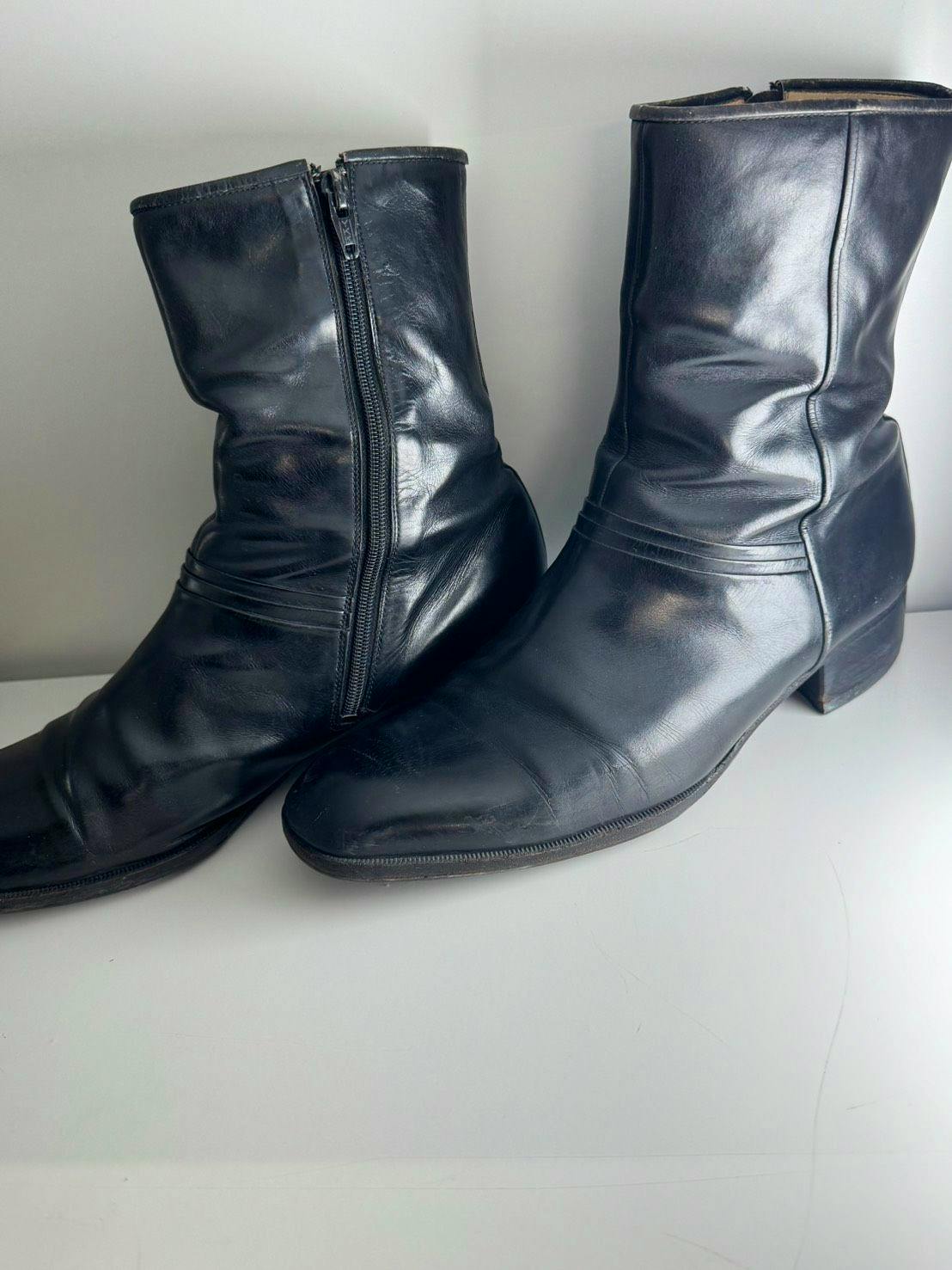 Black vintage leather side-zip boots photographed on a white surface.