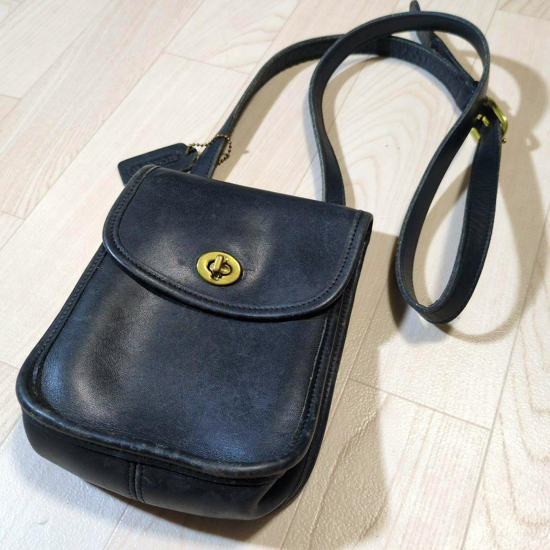 Vintage Coach leather shoulder bag with flap and brass turn-lock, shown with strap and tag on a light floor.