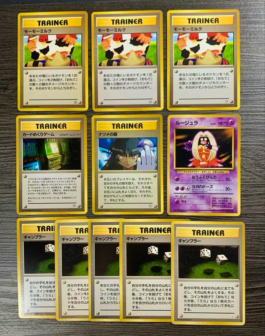 Front faces of eleven vintage Pokémon trading cards from the listed set arranged on a dark wood surface, showing multiple Trainer cards including Sabrina's Eye and one Jynx Pokémon card.