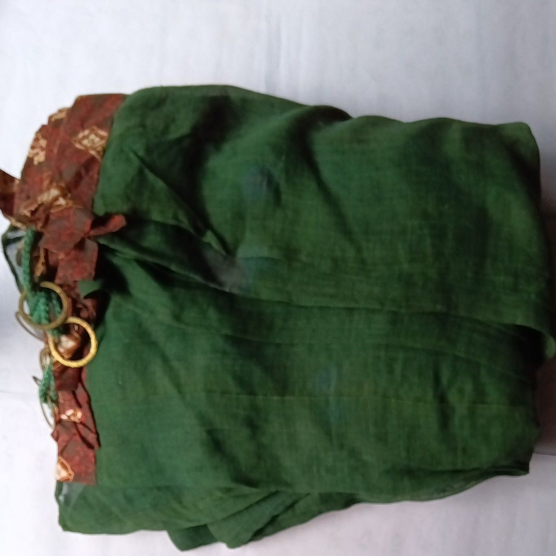 Folded green mosquito net with patterned brown trim and several metal rings visible.