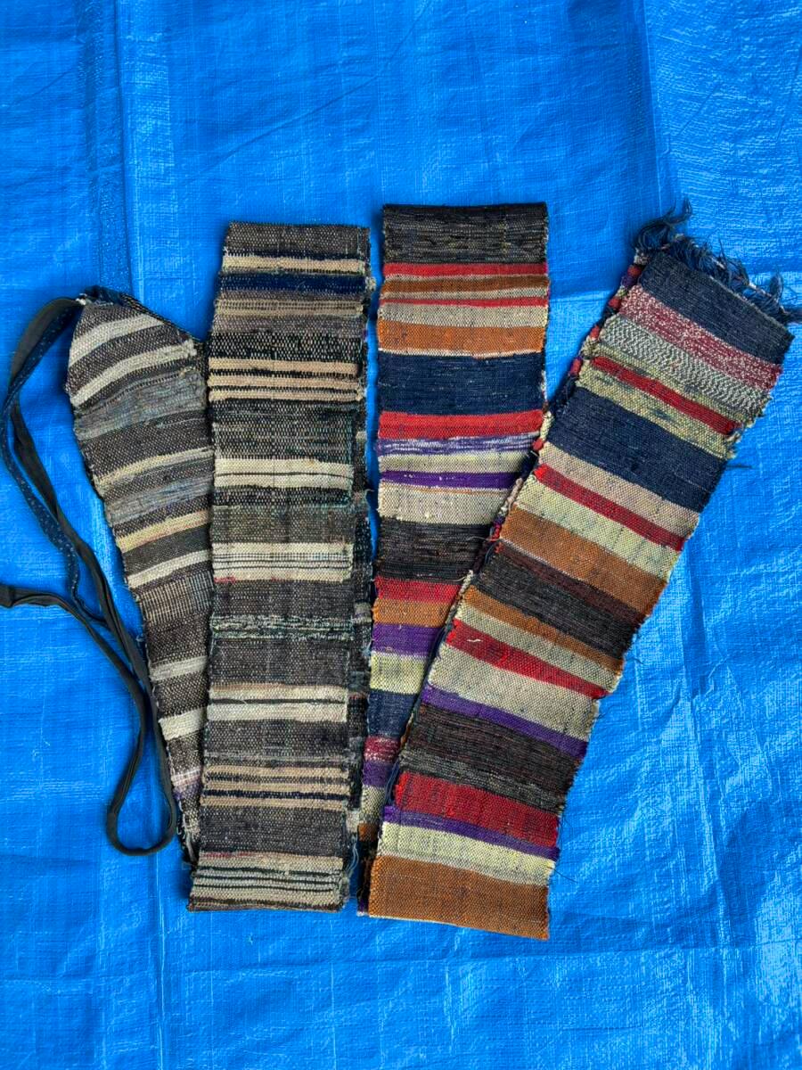 Four long striped woven cotton scarf or patchwork fabric strips laid side-by-side on a blue tarp.