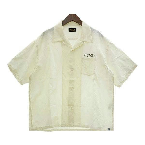 White short-sleeve VISVIM MOTORS CLUB Crosby shirt on a hanger showing the front with 'MOTORS' on the chest.
