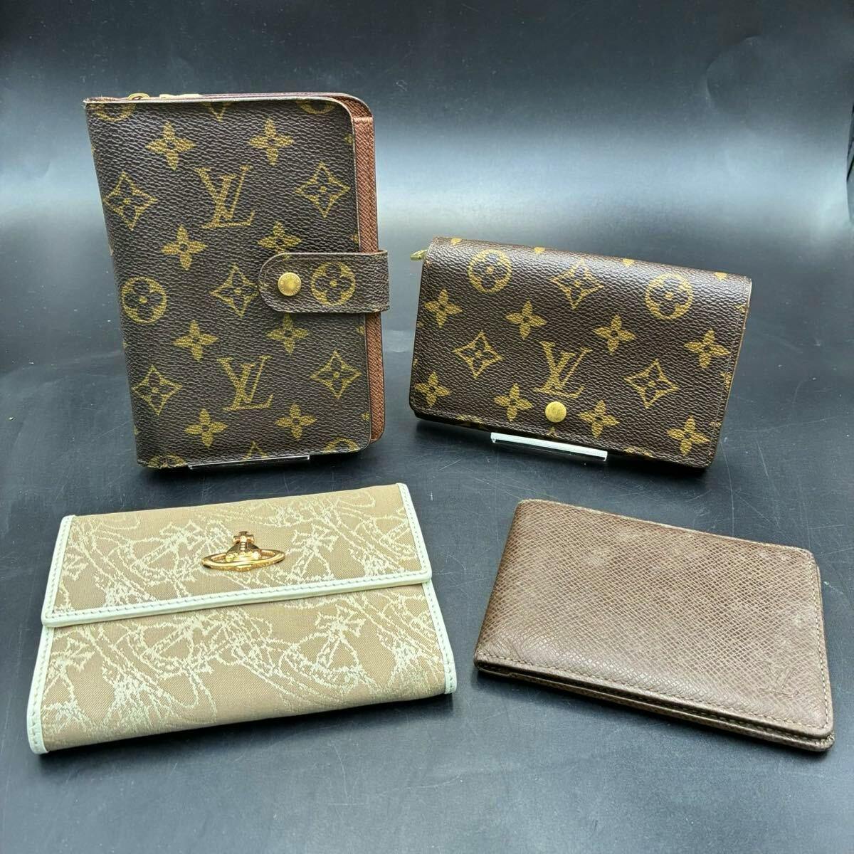 Four wallets arranged on a dark surface, including two Louis Vuitton monogram pieces, a beige Vivienne Westwood wallet, and a plain brown leather wallet.