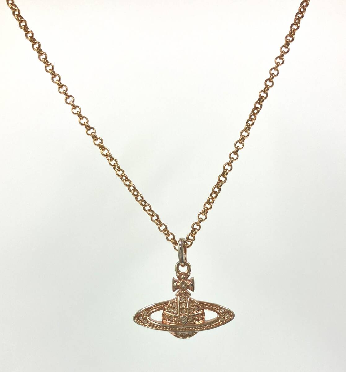Vivienne Westwood gold-tone necklace with an orb pendant set with rhinestones displayed on a white background.