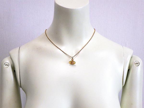 Gold-colored Vivienne Westwood orb pendant necklace displayed on a white mannequin torso.