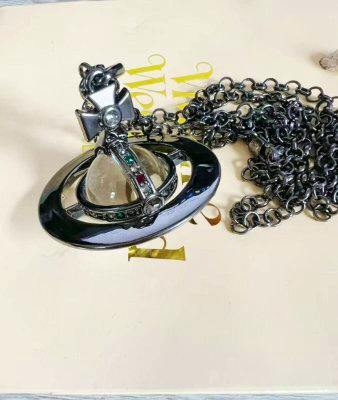 Close-up of the Vivienne Westwood orb necklace pendant in dark metal with its chain laid on a light surface.