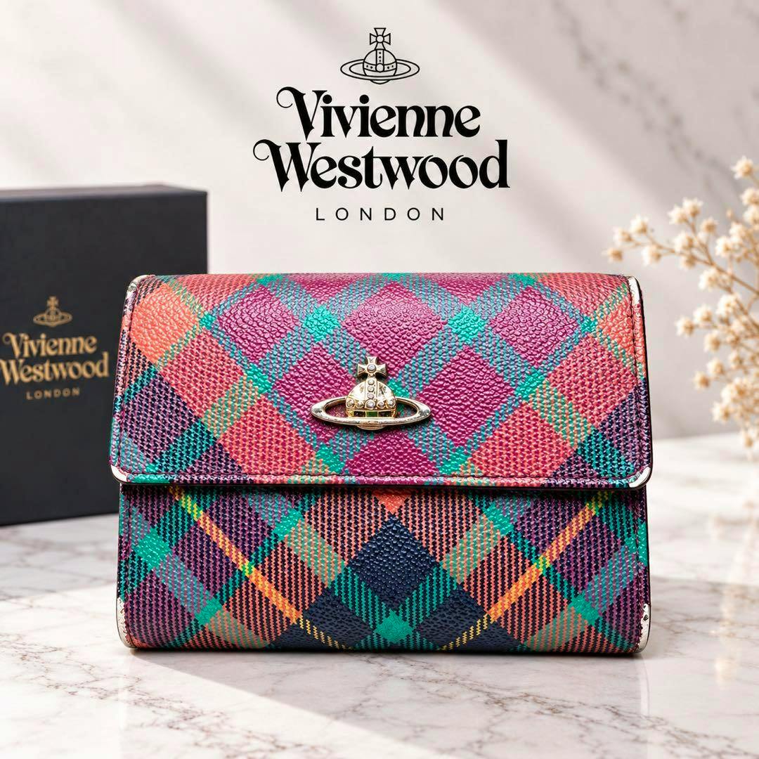 Tartan-check Vivienne Westwood two-fold (bi-fold) wallet with a gold orb emblem on the front, shown on a marble surface with the branded box in the background.